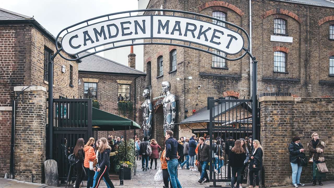 A brick building and a sign that says "Camden Market, with many people walking around