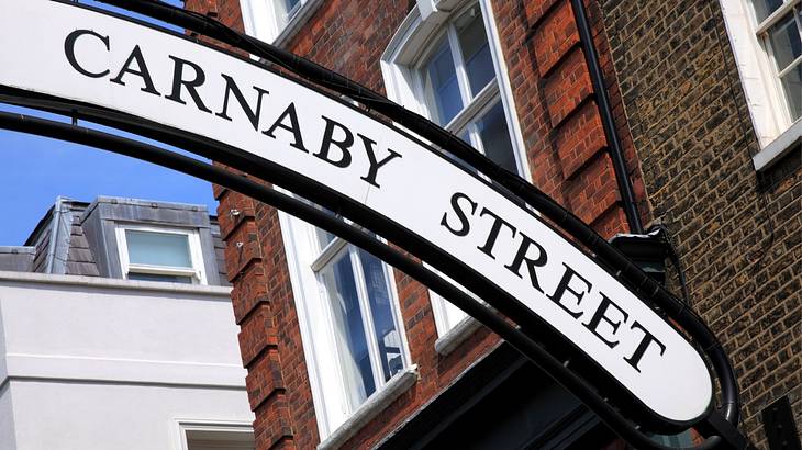 A black and white sign that says "Carnaby Street" next to a brick building