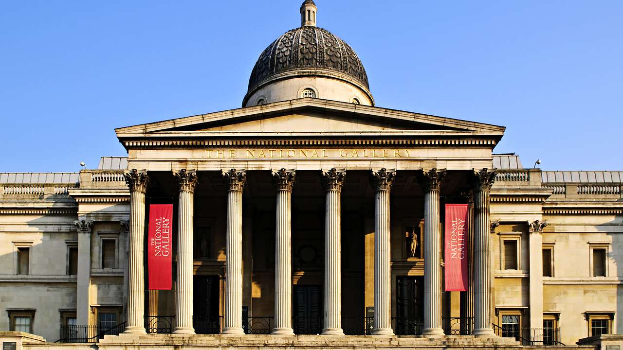 A white building with columns and two red banners at the entrance and a dome