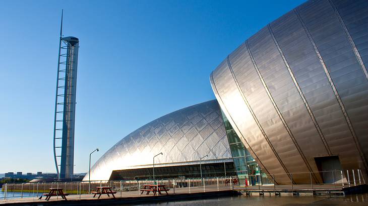 A large building with a domed, metallic silver surface against clear blue skies