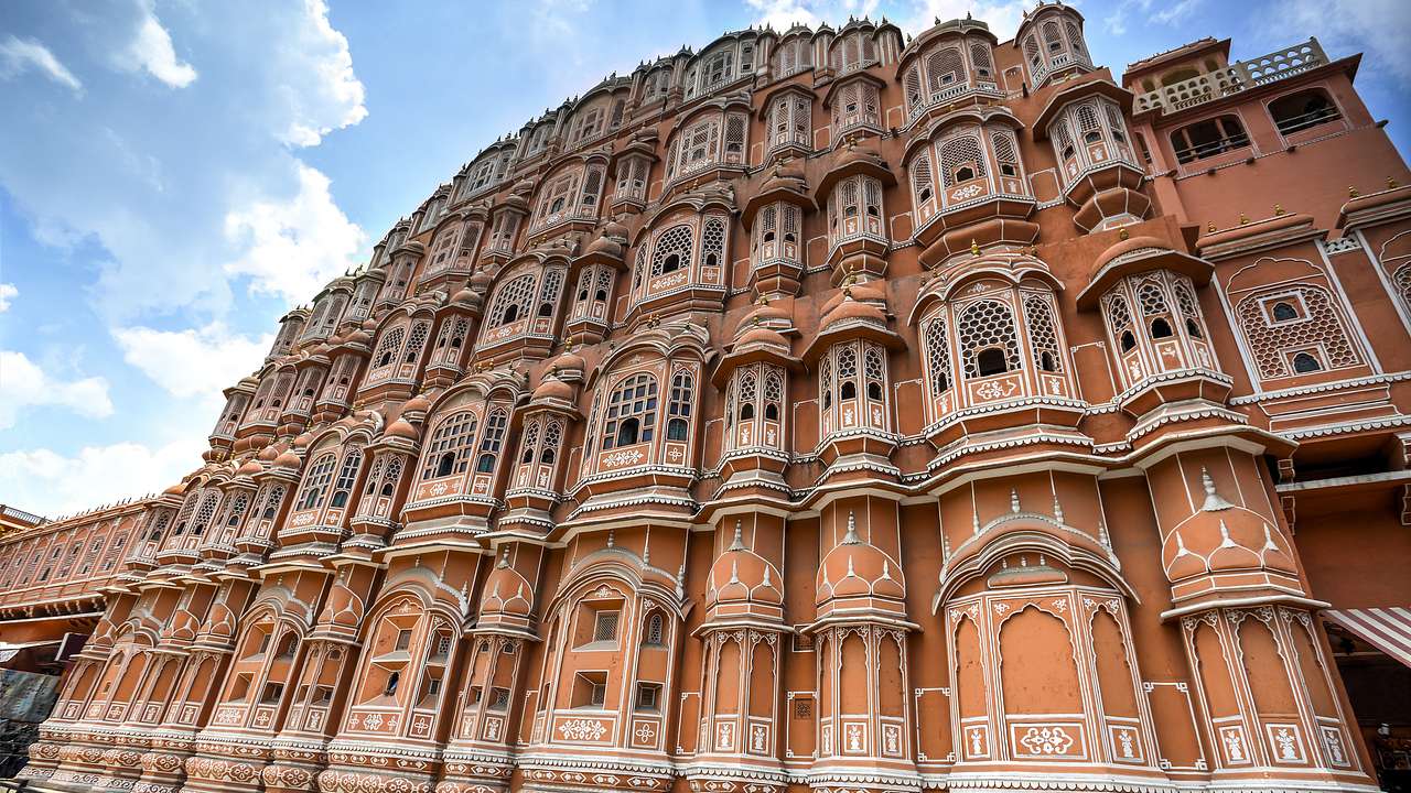 A unique exterior of a red and pink-colored palace made of sandstone under blue skies