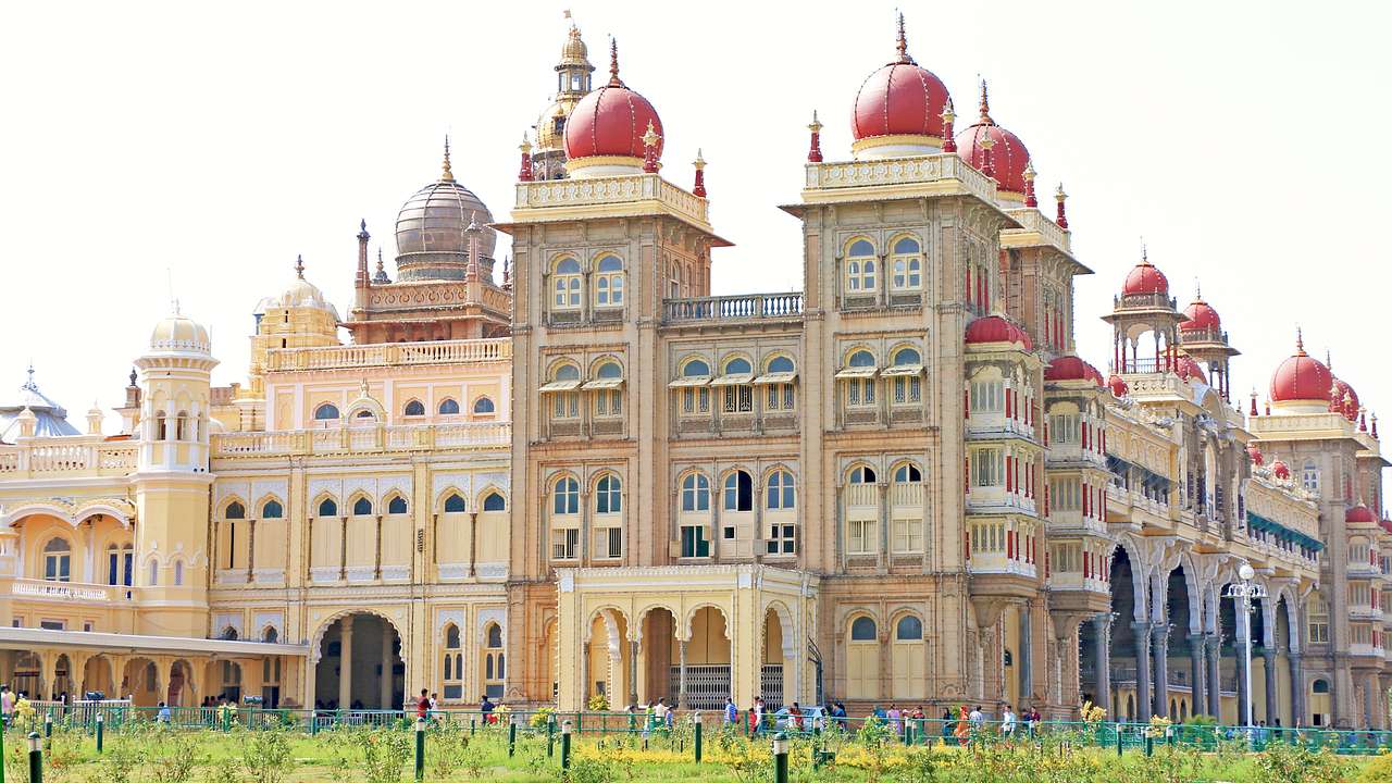 Side view of a palace with red domes facing a green lawn