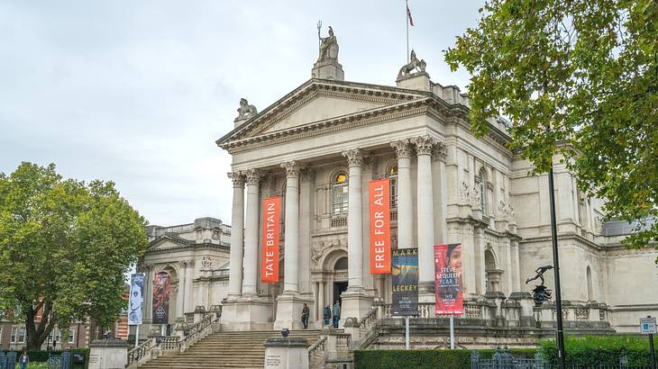 A stone building with columns and orange banners that say "Tate Britain"