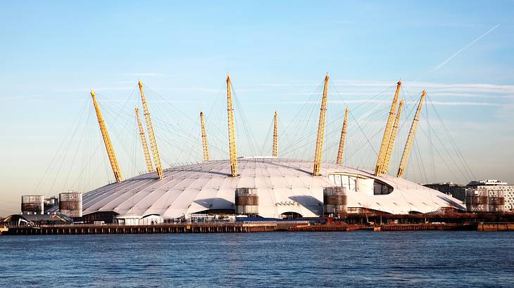 A dome-shaped structure with yellow spikes on the top next to a river