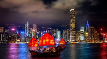 A harbour with a ship and buildings in background at night, Hong Kong