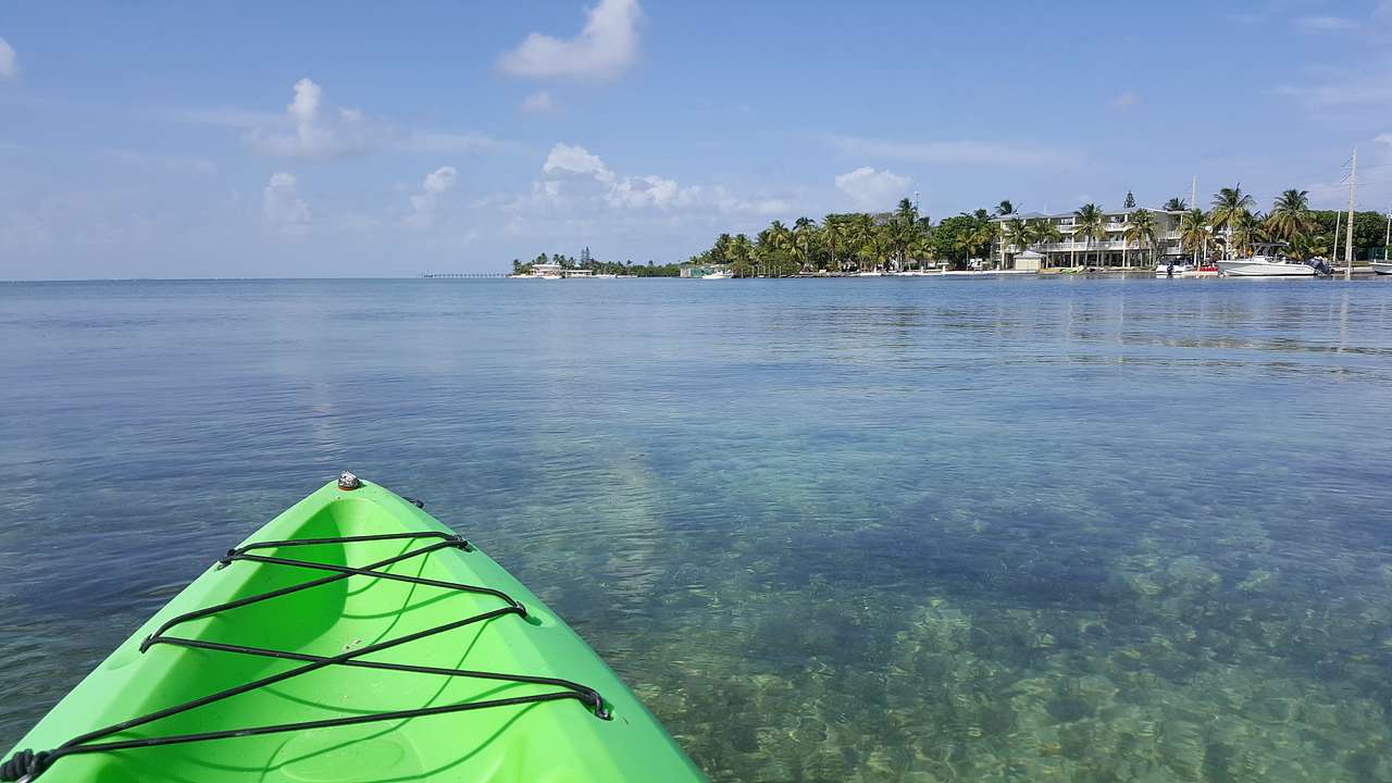 A green kayak in the water and an island with trees in the distance