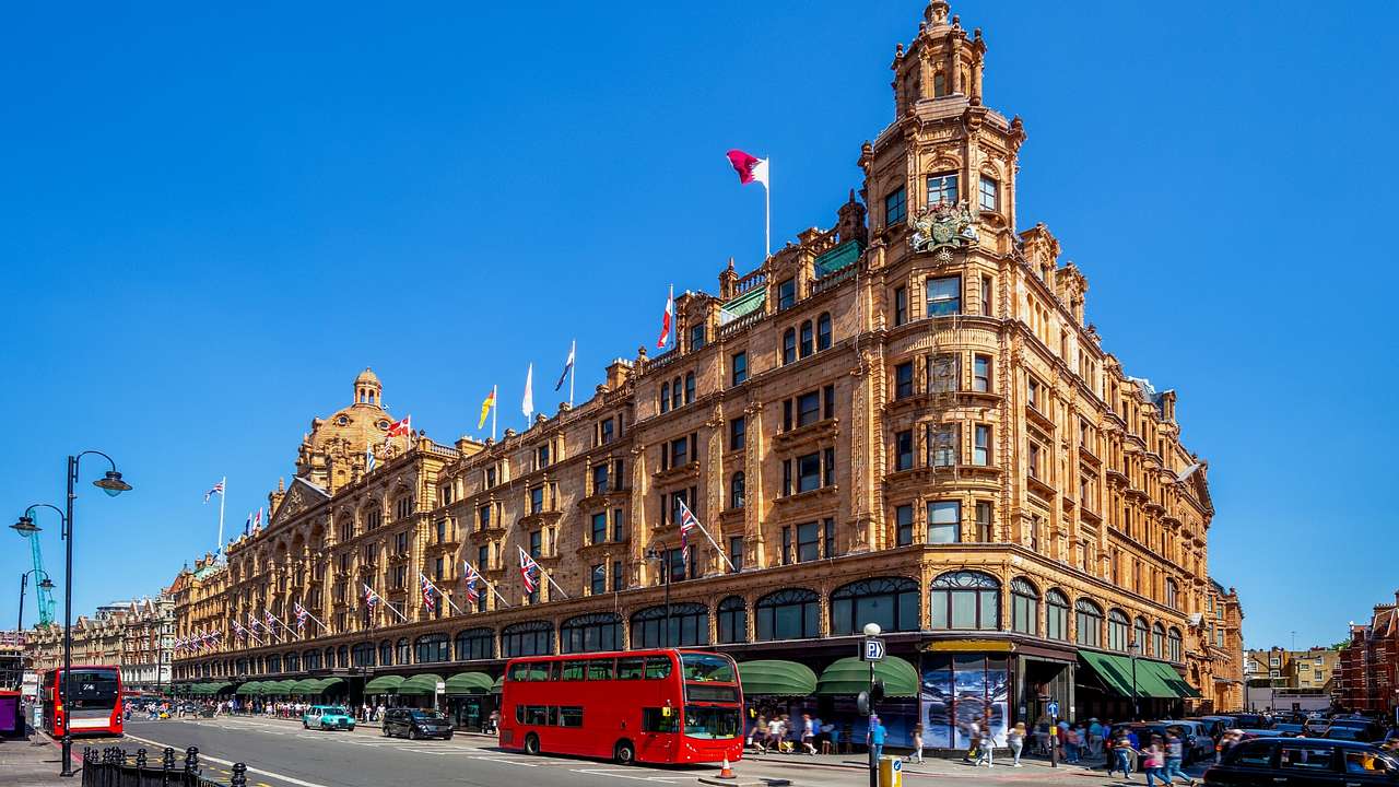 A large and regal department store building with red busses and other cars in front