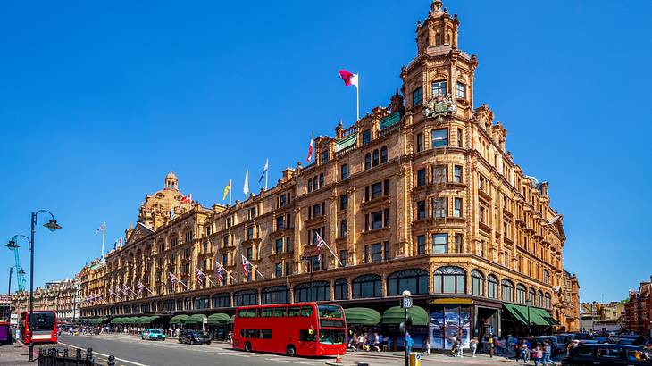 A large and regal department store building with a red bus another cars in front