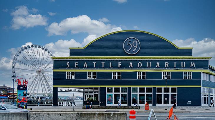 A walkway to a blue building with the sign "Seattle Aquarium"