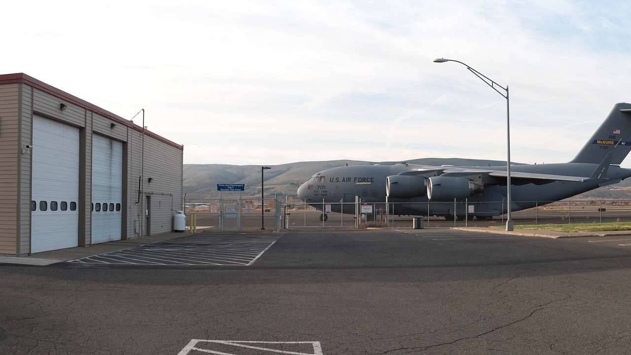 A military aircraft in a airport next to some small buildings