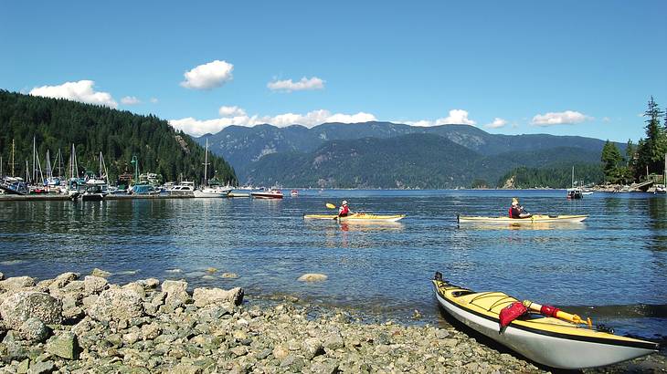 A lake with boats and kayaks on it surrounded by trees and hills