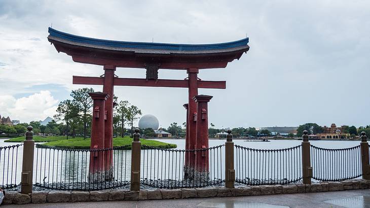 A large red structure with a fence around it and a body of water in the background