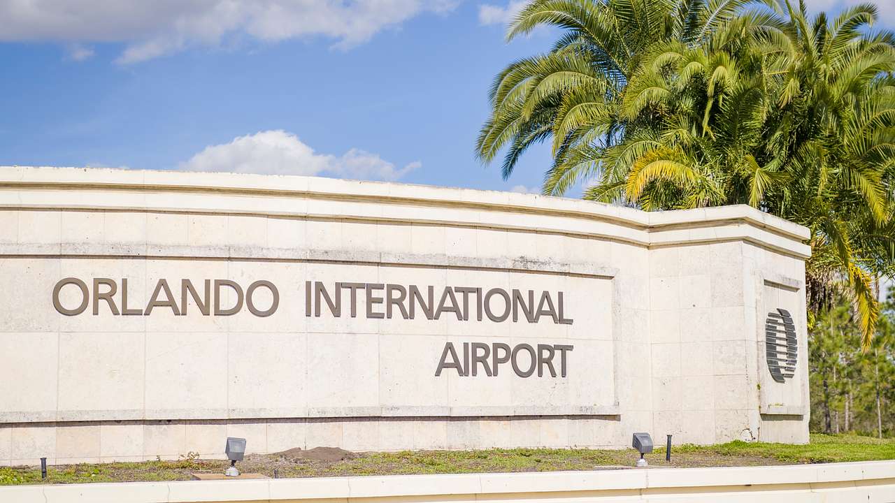 A white wall with the sign "Orlando International Airport" with palm trees