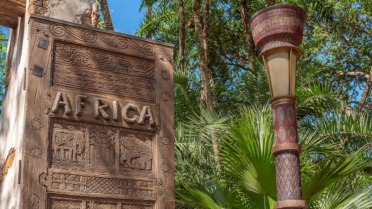A stone post with the word "Africa" and a lamp post and palm trees