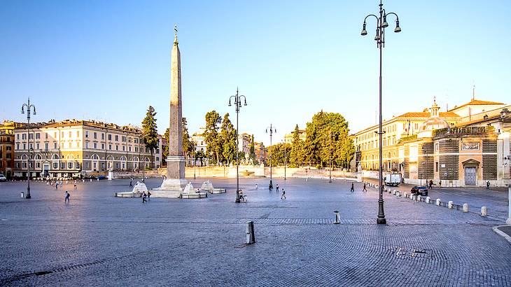Morning sun illuminating buildings, trees and a monument in the middle of a square Morning sun illuminating buildings, trees and a monument in the middle of a square