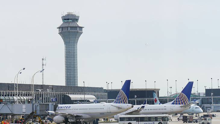 A group of airplanes at an airport with a tower in the background
