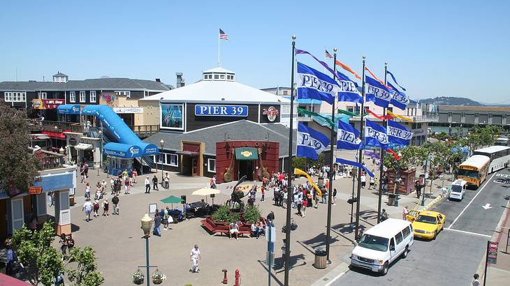 A busy public square with people and cars parked nearby, under a clear blue sky A busy public square with people and cars parked nearby, under a clear blue sky