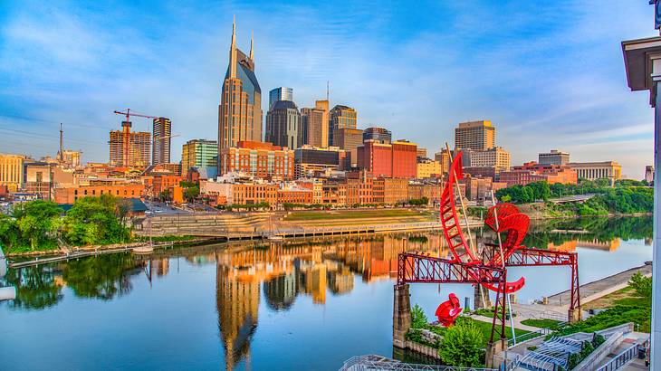 A city skyline reflected on a river in front of it under a blue sky A city skyline reflected on a river in front of it under a blue sky