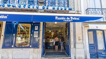 The exterior of a bakery with a blue design and a "Pastéis de Belém" sign