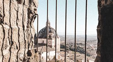 Looking through bars at a church dome top from above, Montefiascone, Italy