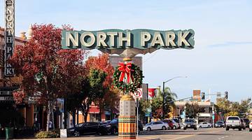 A sign "North Park" over a street with a Christmas wreath decoration