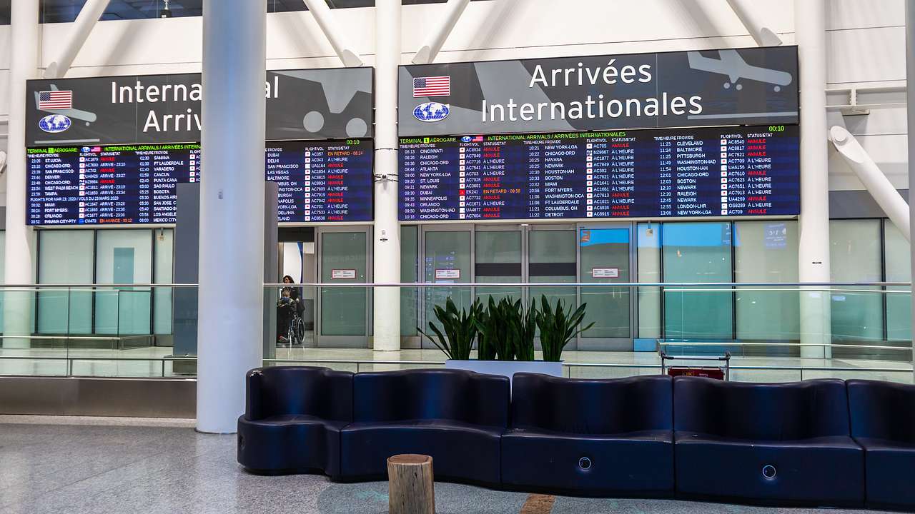 Arrival and departure sign with plants and seating in an airport