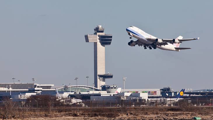 An airplane flying with a tower in the background