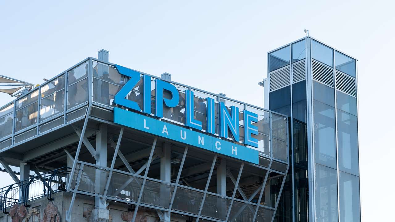A blue sign "Zipline Launch" on a building with many windows