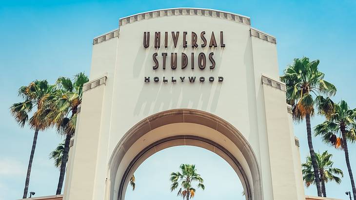 A large stone building with the sign "Universal Studios Hollywood" and palm trees