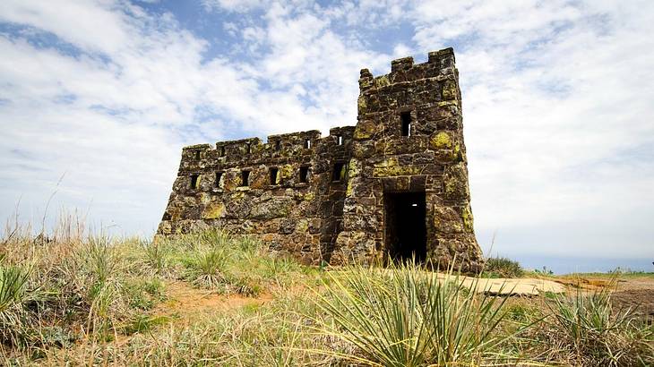 A small castle-like structure with grass around it on a cloudy day