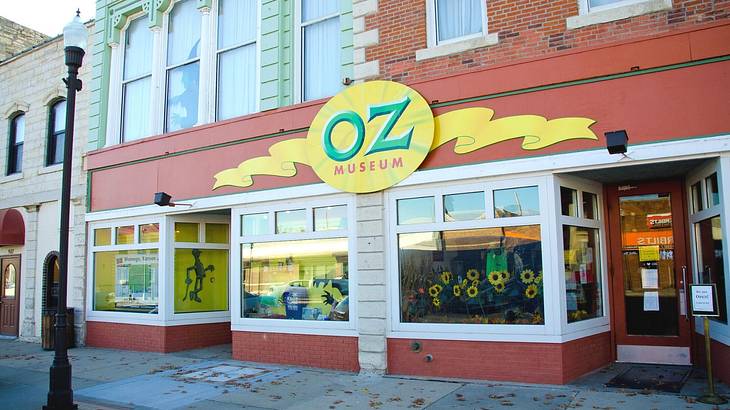 A museum front with sunflowers in the windows and a sign that says "Oz Museum"