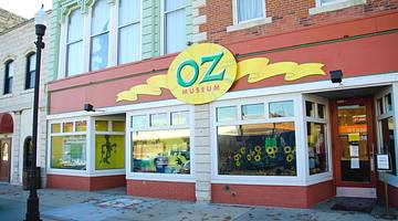 A museum front with sunflowers in the windows and a sign that says "Oz Museum"