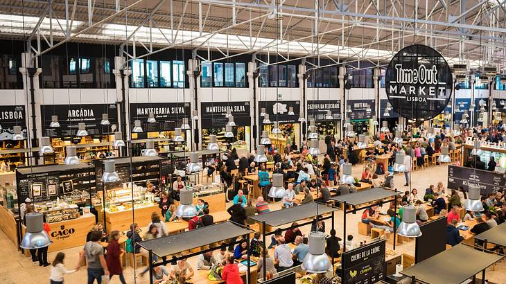 An indoor market with lots of people at tables and a sign that says "Time Out Market"