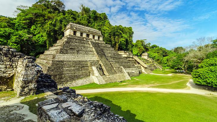 Ruins of a pyramid with steps surrounded by greenery