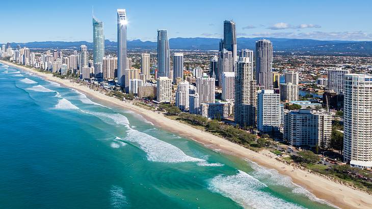 An aerial photo of a stunning city skyline along blue water and white sand