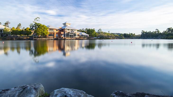 A building on calm water surrounded by greenery