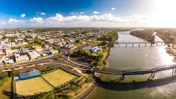 Aerial view of Bundaberg with buildings, cars on a street, and bridges across a river