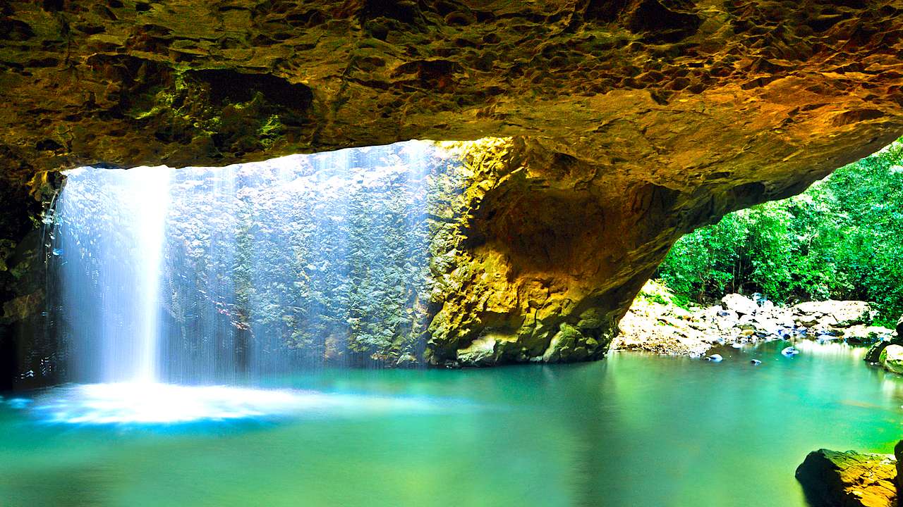A view from the cave of the Natural Bridge over water with a waterfall