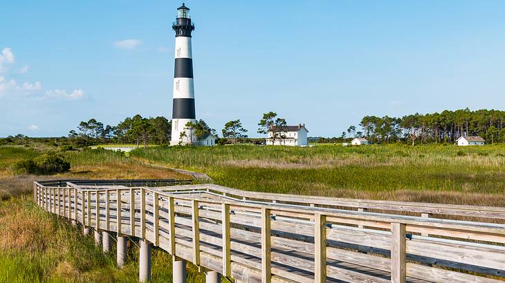 A lighthouse at the end of a long walkway, surrounded by marshland A lighthouse at the end of a long walkway, surrounded by marshland