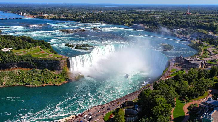 Aerial view of a massive waterfall crashing into a river and surrounded by greenery