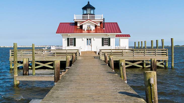 A square cottage style lighthouse at the end of a pier