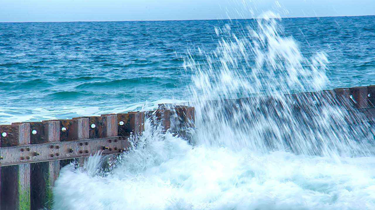 A wave breaking on a jetty in the water