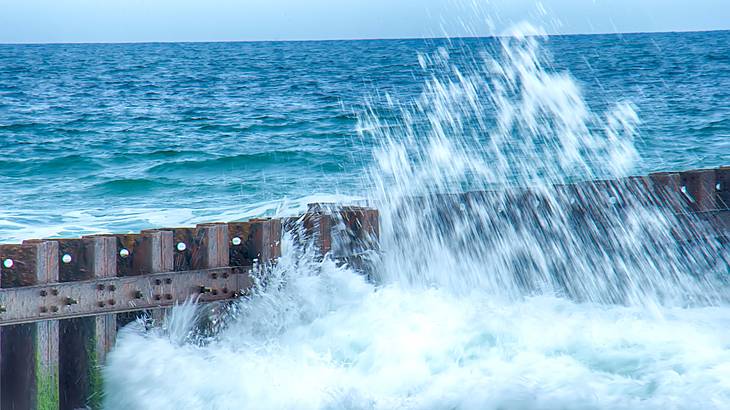 A wave breaking on a jetty in the water