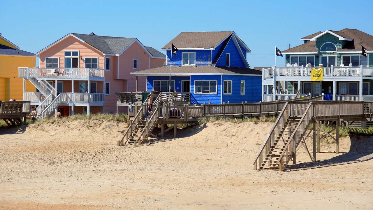 A row of colorful houses on a sandy beach under a blue sky on a sunny day