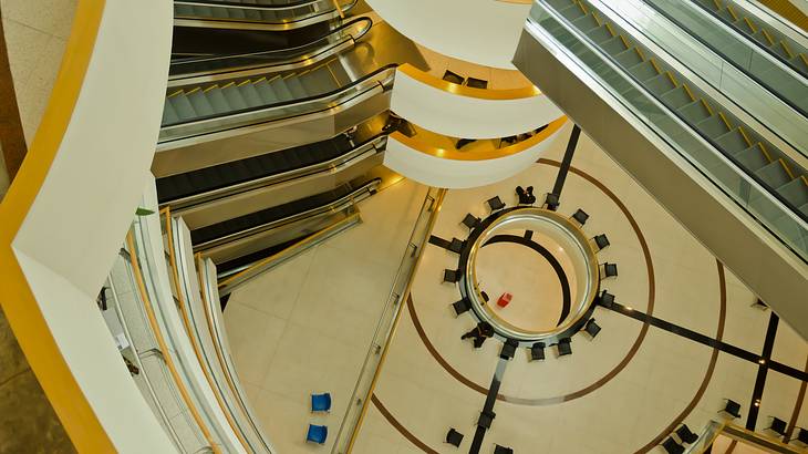 View of a building's winding hallways with escalators below from the top floor View of a building's winding hallways with escalators below from the top floor