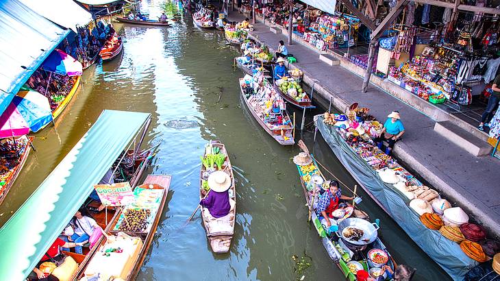 Boats with tourists going down the middle of market stalls on water