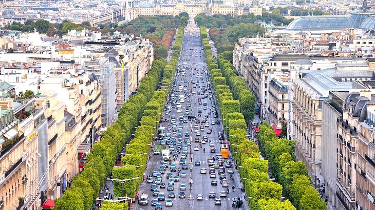 Aerial view of a city skyline with a busy street in the middle lined with greenery