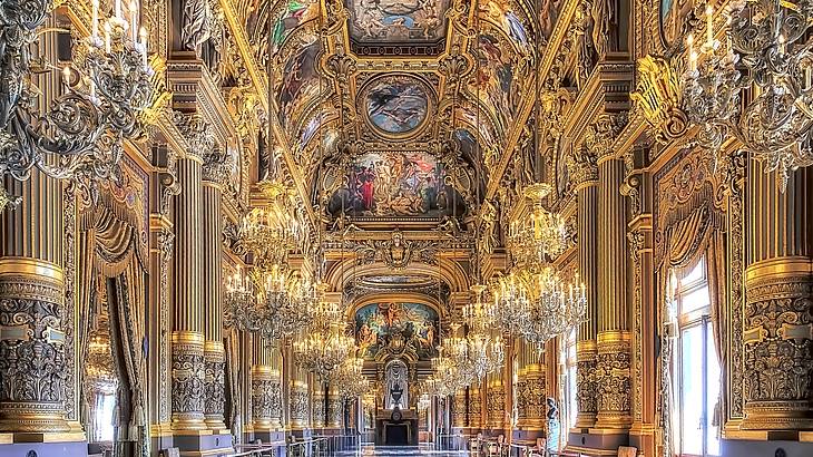 An opera house's interior with grand chandeliers and Baroque paintings on the ceiling