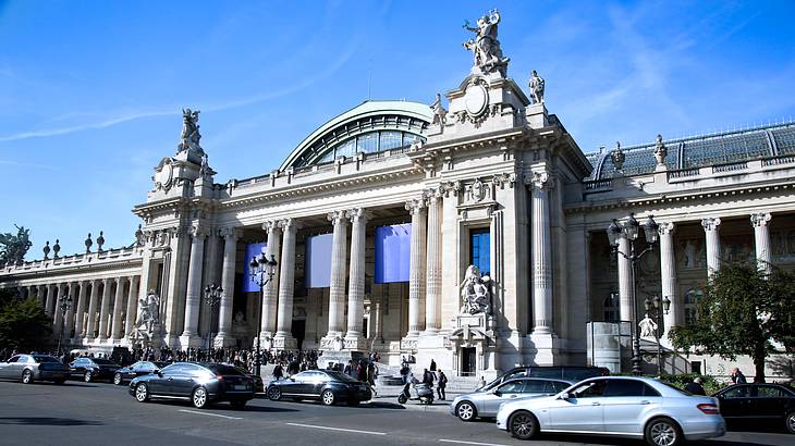 A museum's facade with people outside and cars on the road