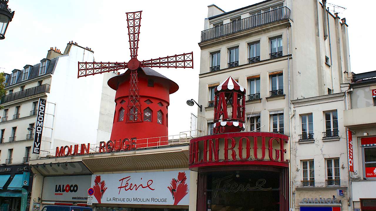 A cabaret house complete with a red facade & windmill and buildings behind